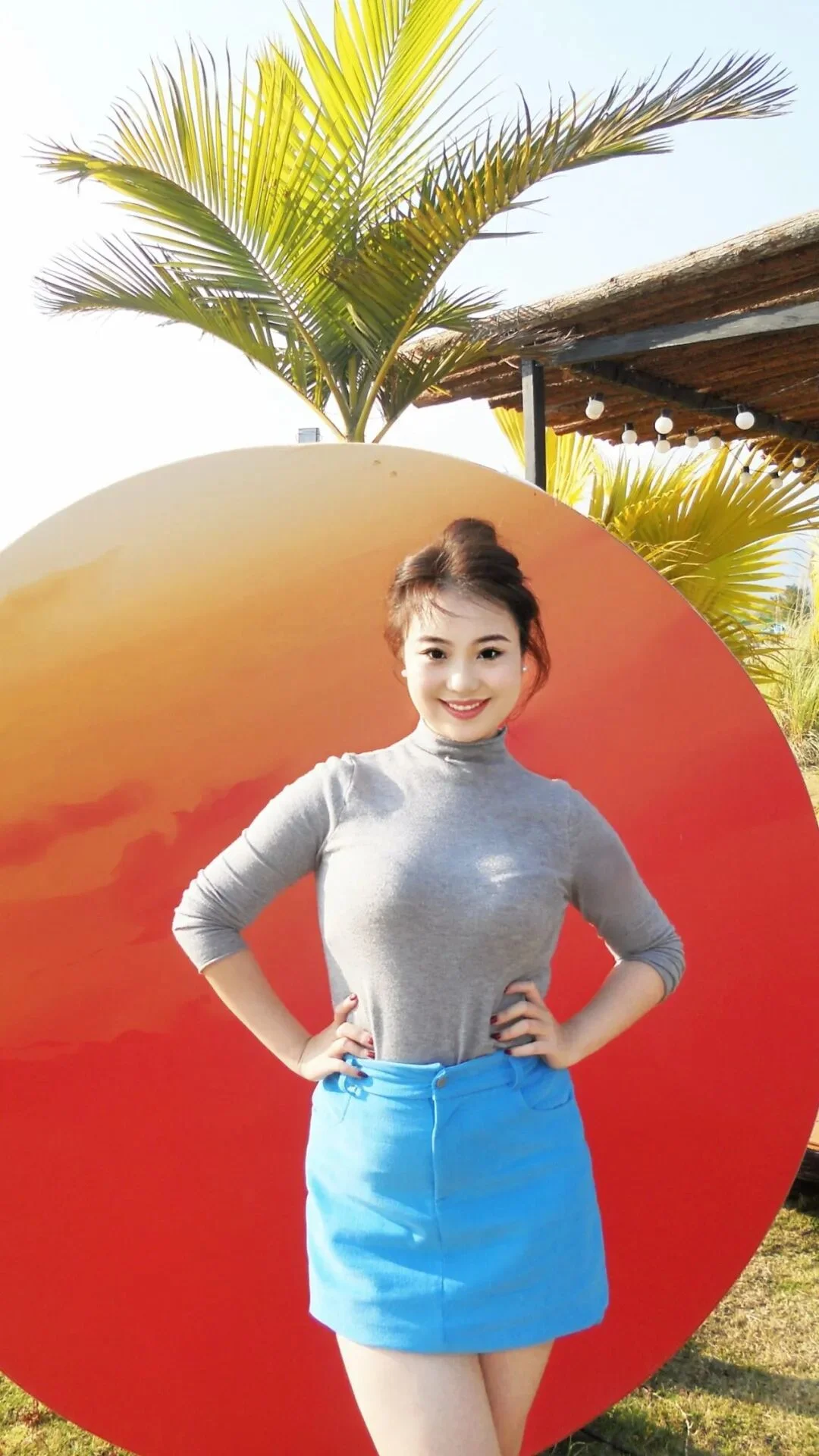 7. De pies con pies cruzados, manos en las caderas, mirando a la cámara y sonriendo